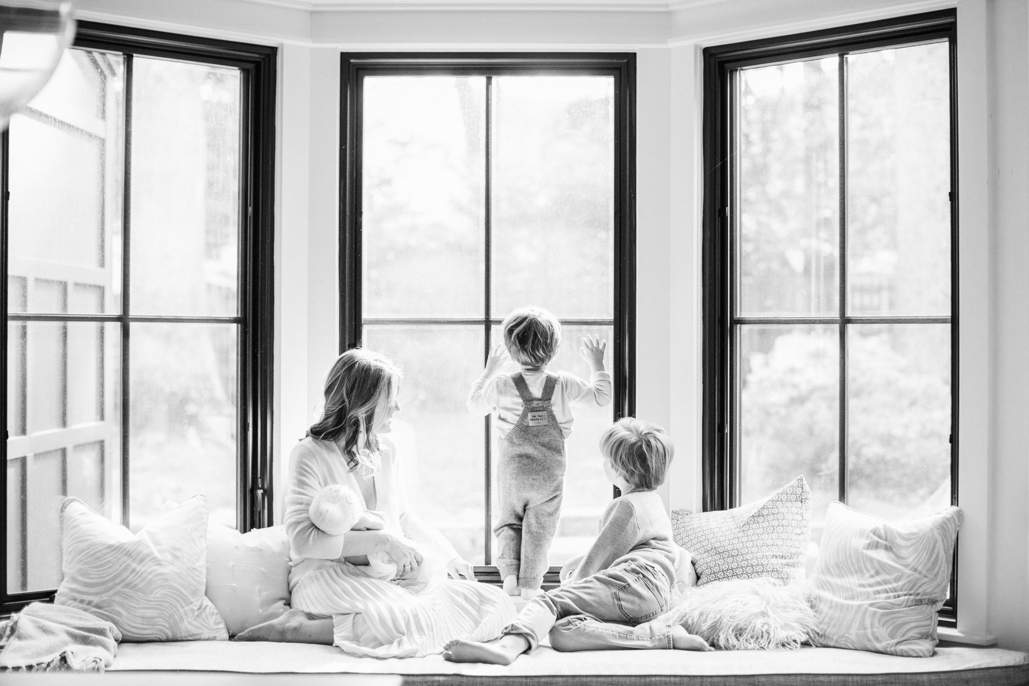 Black and white portrait of mom with the children sitting on window seat. Photo by Chevy Chase DC newborn photographer, LRG Portraits.