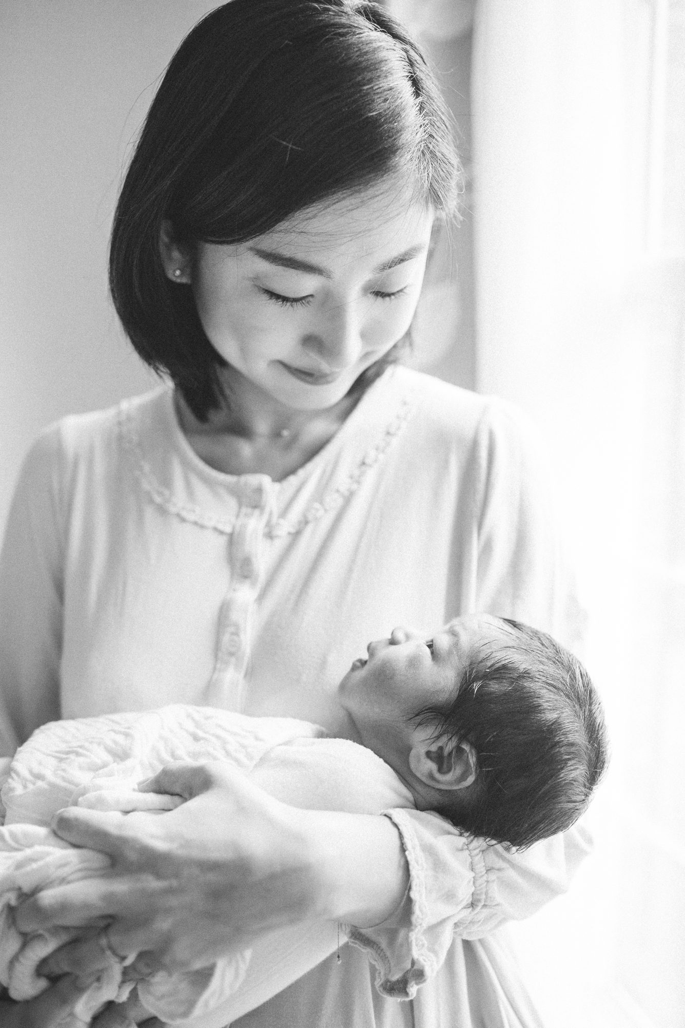 Black and white image of Mom holding baby during in-home newborn session. Photo by LRG Portraits.