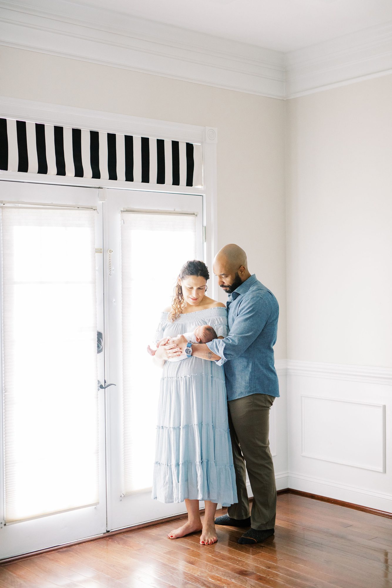 New parents holding baby boy during in-home lifestyle newborn session with LRG Portraits.