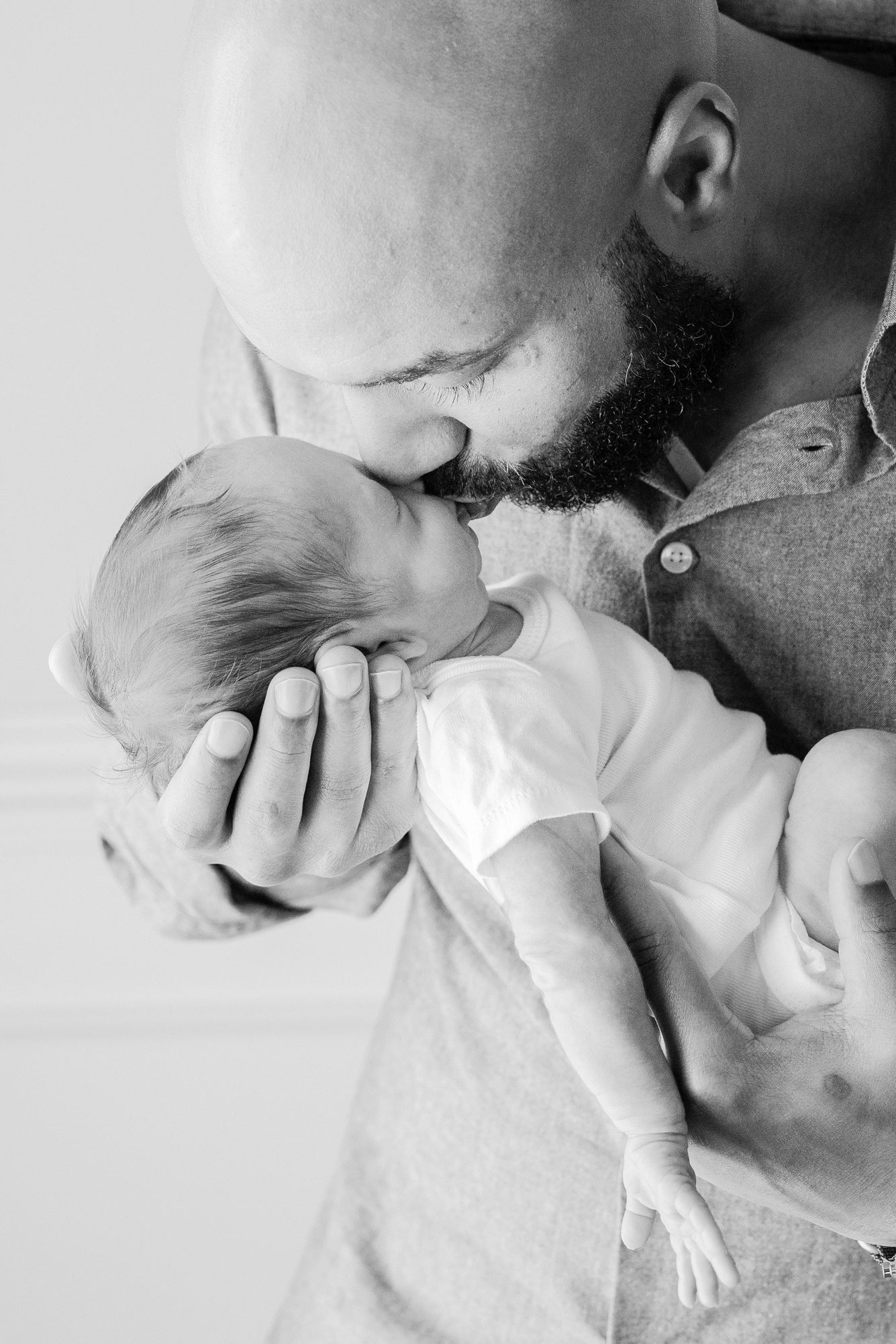 Black and white image of Dad kissing baby. Photo by LRG Portraits.