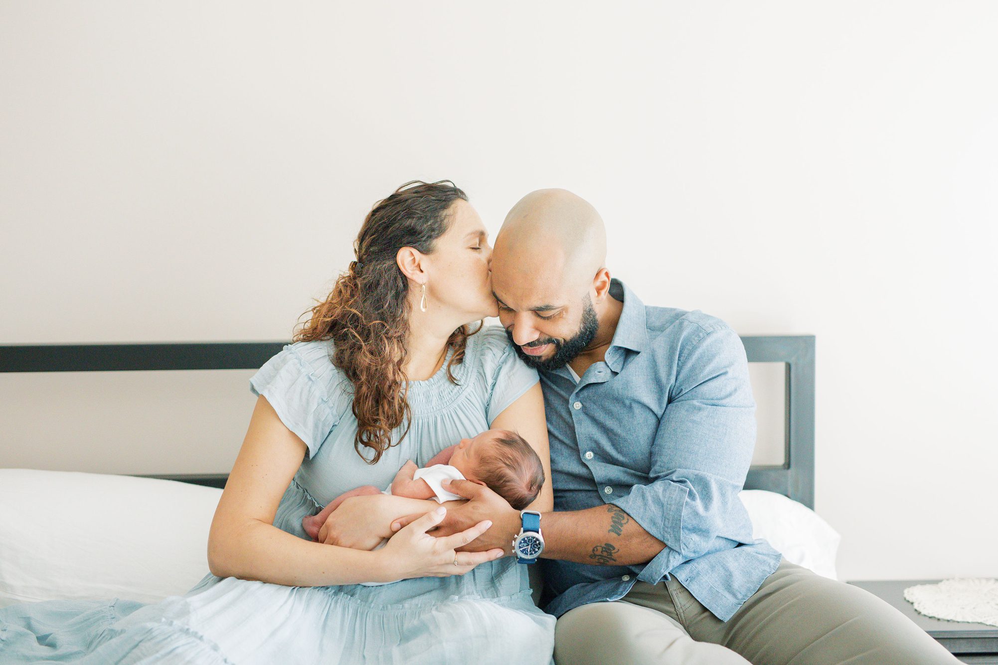Mom and Dad cuddling with newborn on bed. Photo by Washington DC baby photographer, LRG Portraits.