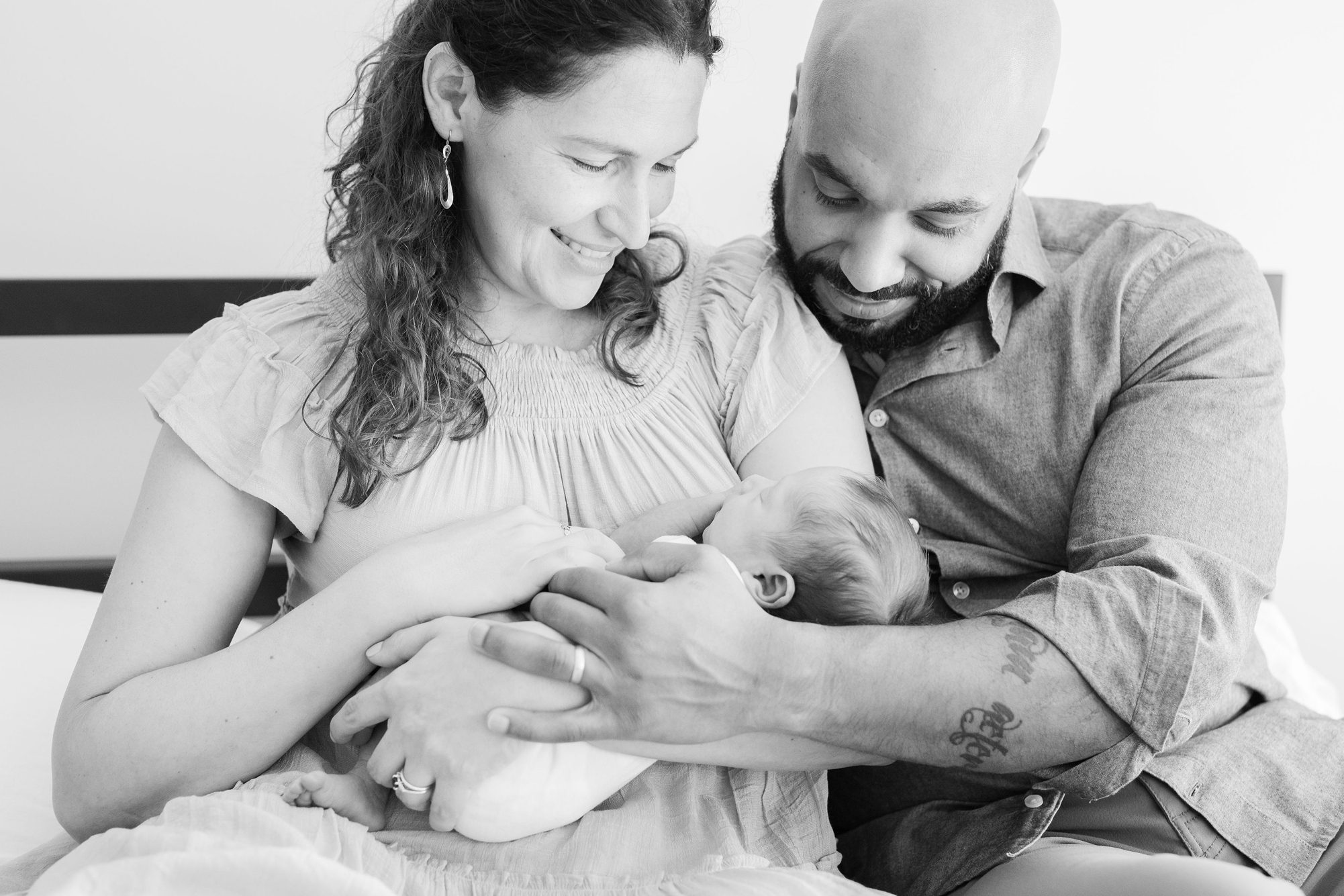 Black and white portrait of Mom and Dad with baby. Photo by LRG Portraits