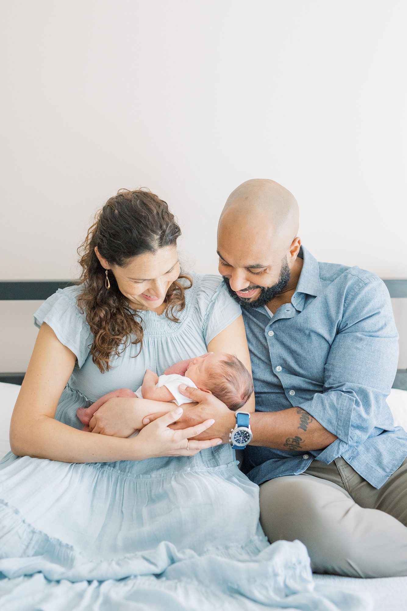 Mom and Dad smiling at newborn baby boy during Washington DC in-home newborn session. Photo by LRG Portraits