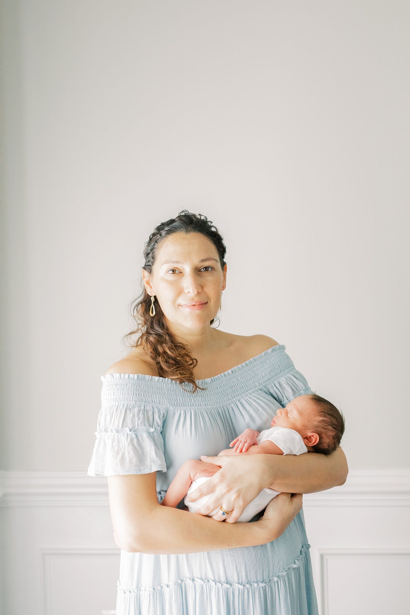 Mom holding newborn while she wears beautiful blue maxi dress. Photo by LRG Portraits