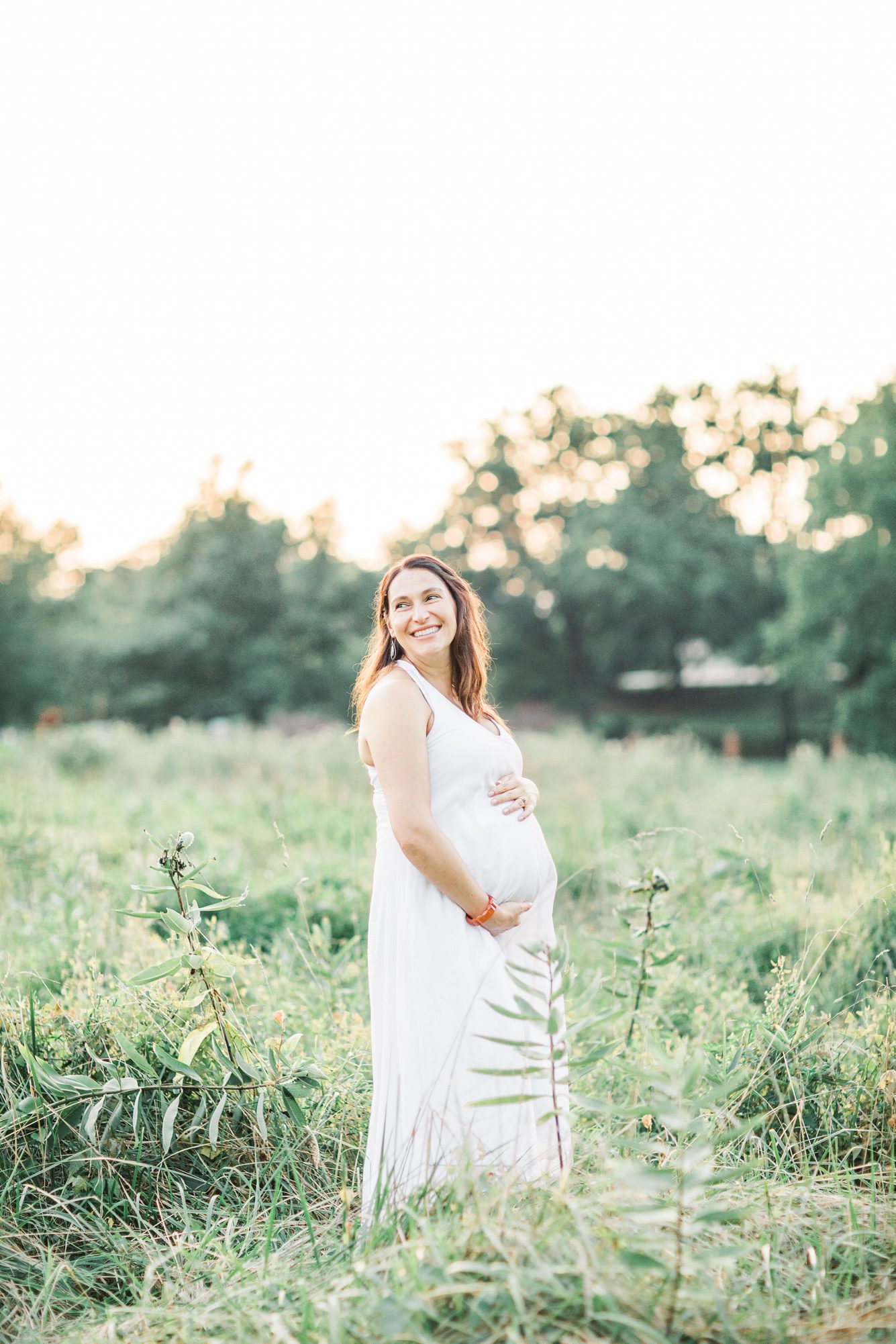 Beautiful mom smiling during field maternity session in Rock Creek Park outside of Washington DC. Photo by LRG Portraits.