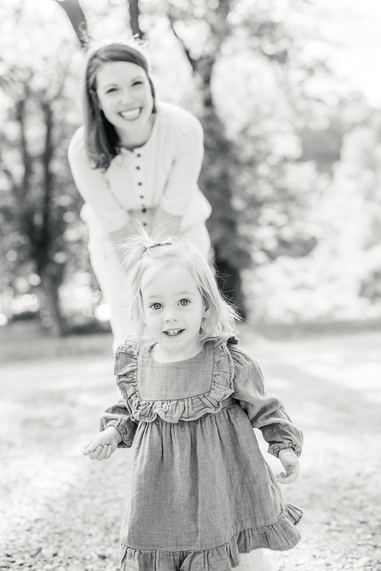 Black and white image of Mom smiling at little girl. Photo by LRG Portraits.