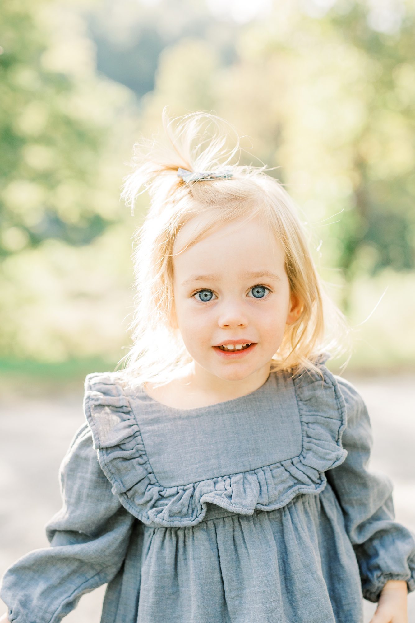 Closeup of little girl in blue dress during family session. Photo by LRG Portraits.
