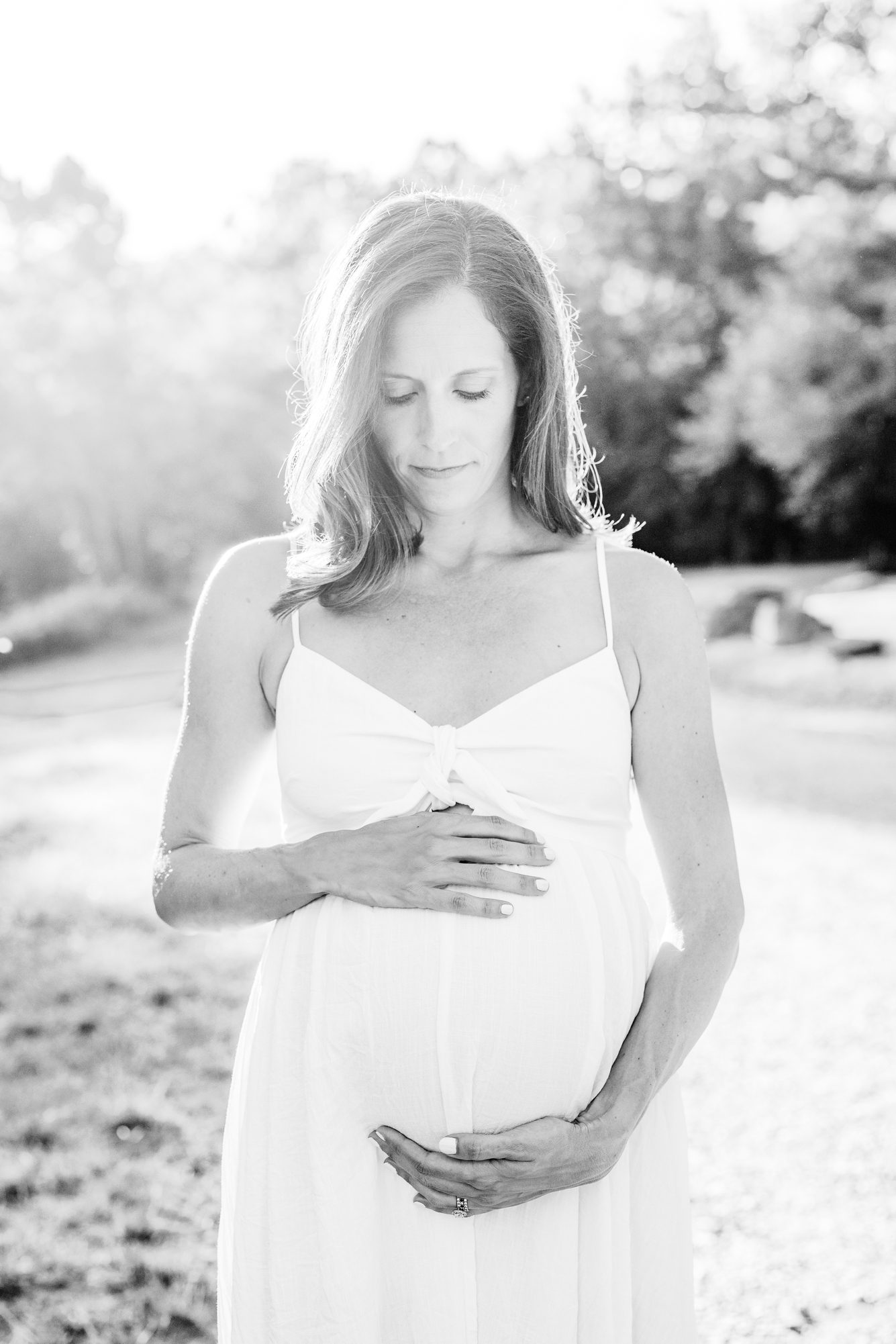 Black and white image of expecting mom holding bump. Photo by LRG Portraits.