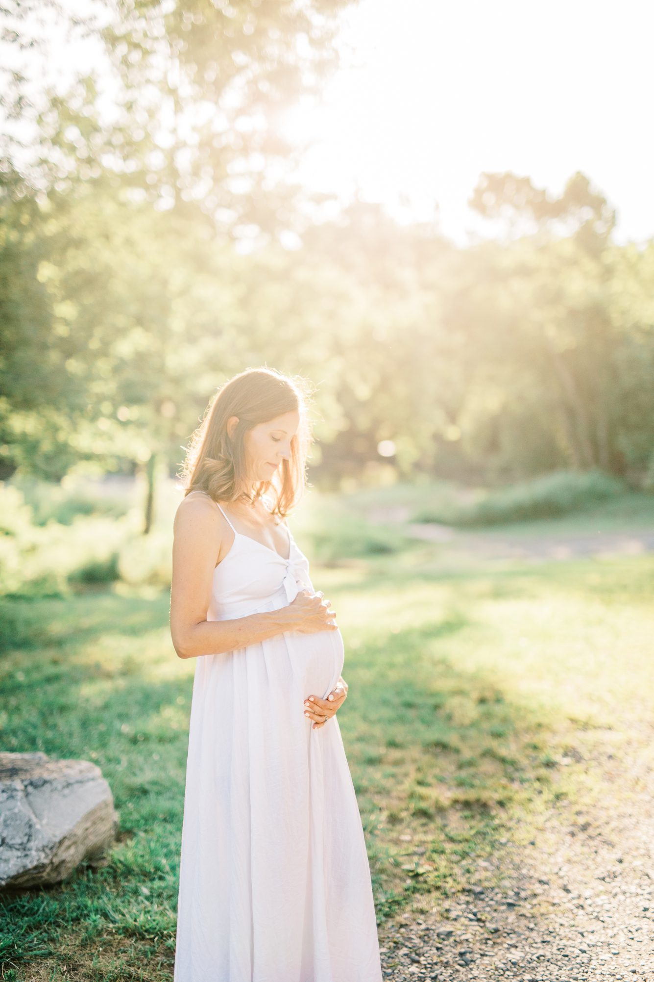 Sun-drenched image of pregnant mom with hands on her bump by Washington DC maternity photographer, LRG Portraits.