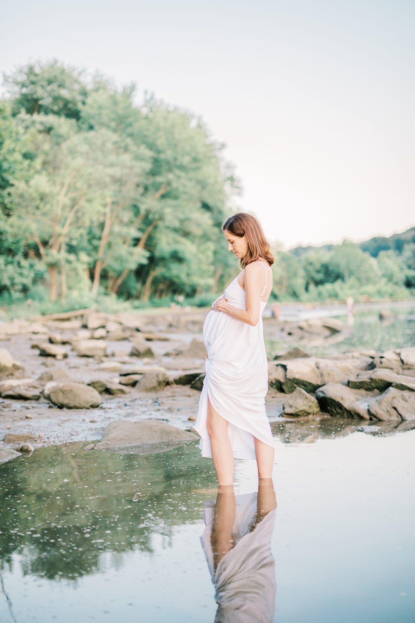 Mom walking in river with reflection in water during Washington DC maternity session. Photo by LRG Portraits.
