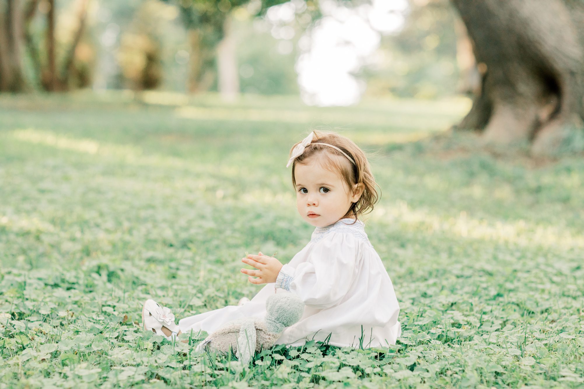 Little girl sitting in grass during family session. Photo by LRG Portraits.