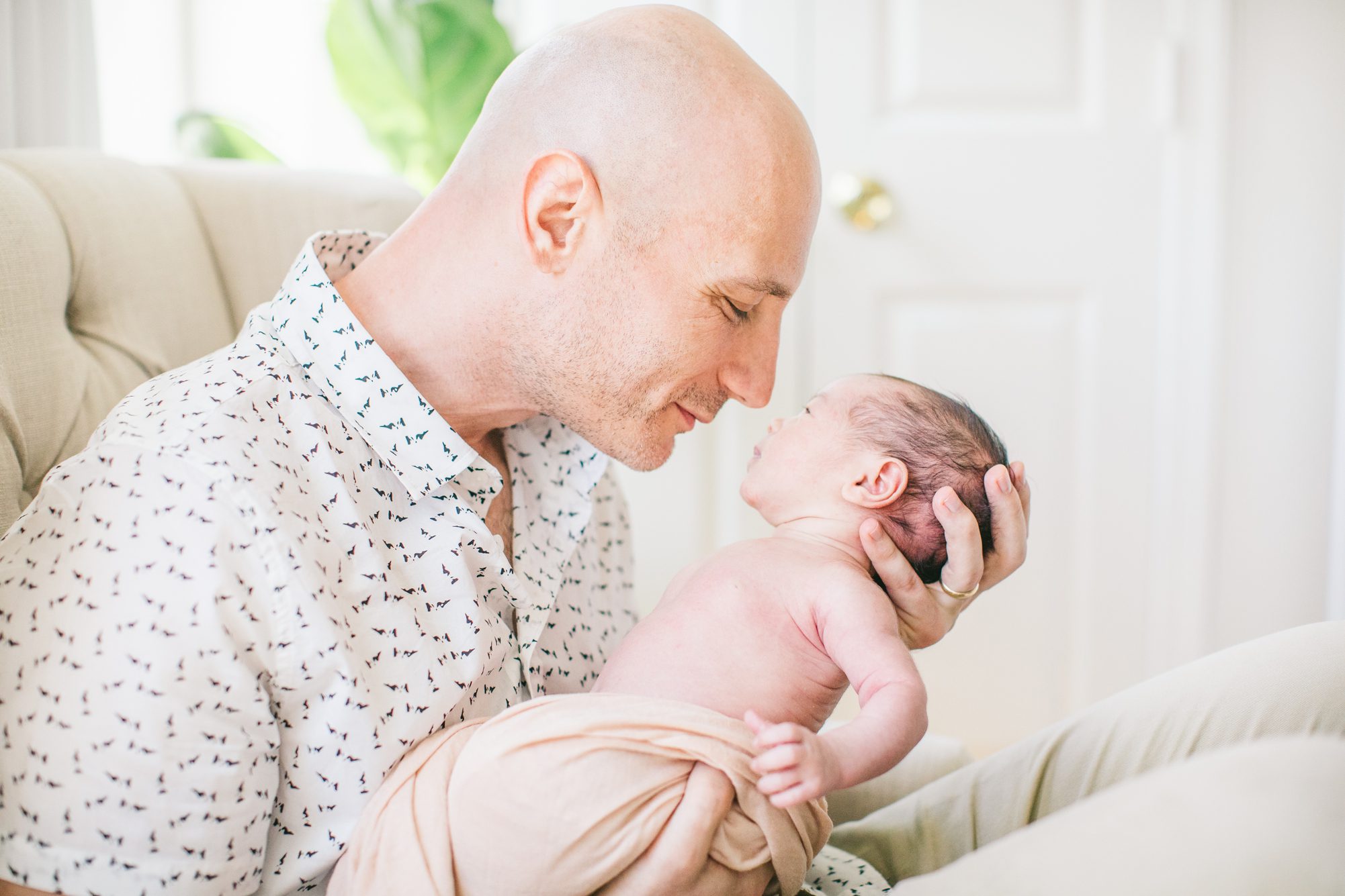 Dad holding newborn near his face and smiling at her during newborn session. Photo by LRG Portraits.