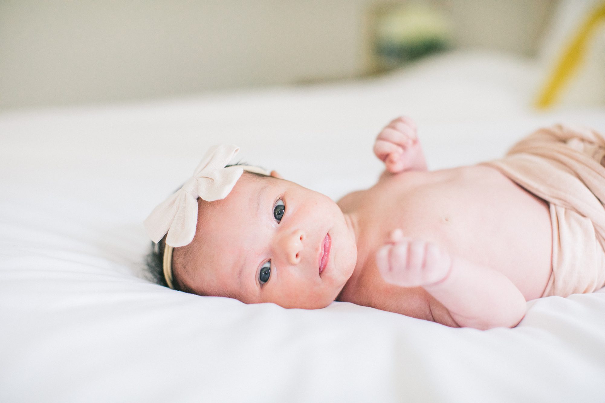 Sweet image of baby girl awake on bed during newborn session. Photo by LRG Portraits.