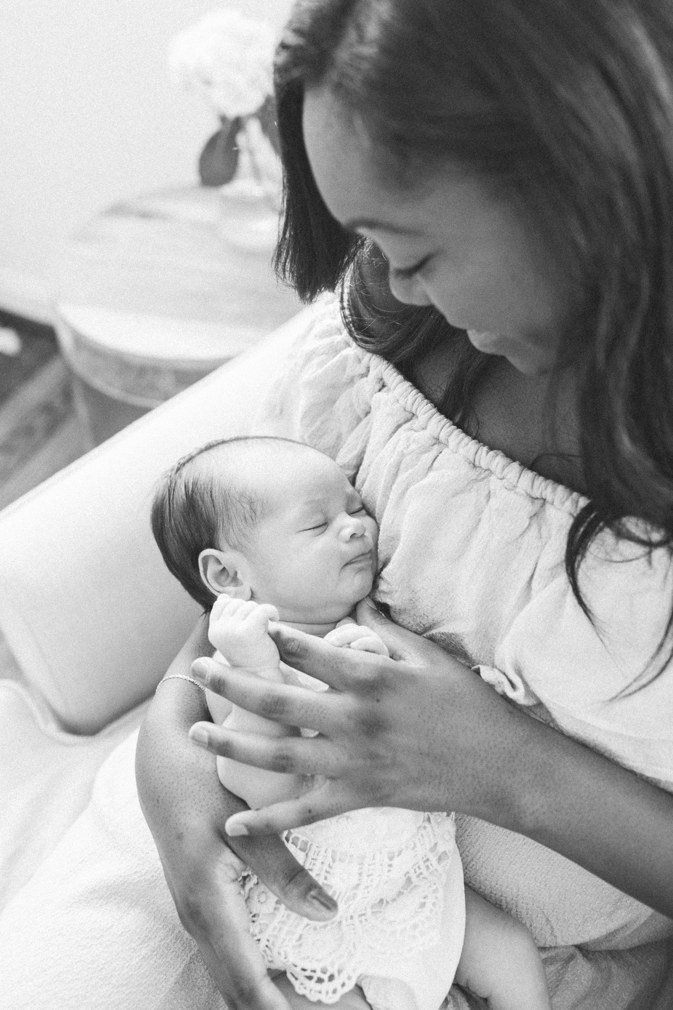 Black and white image of Mom holding baby's hand in nursery. Photo by Washington DC newborn photographer, LRG Portraits.
