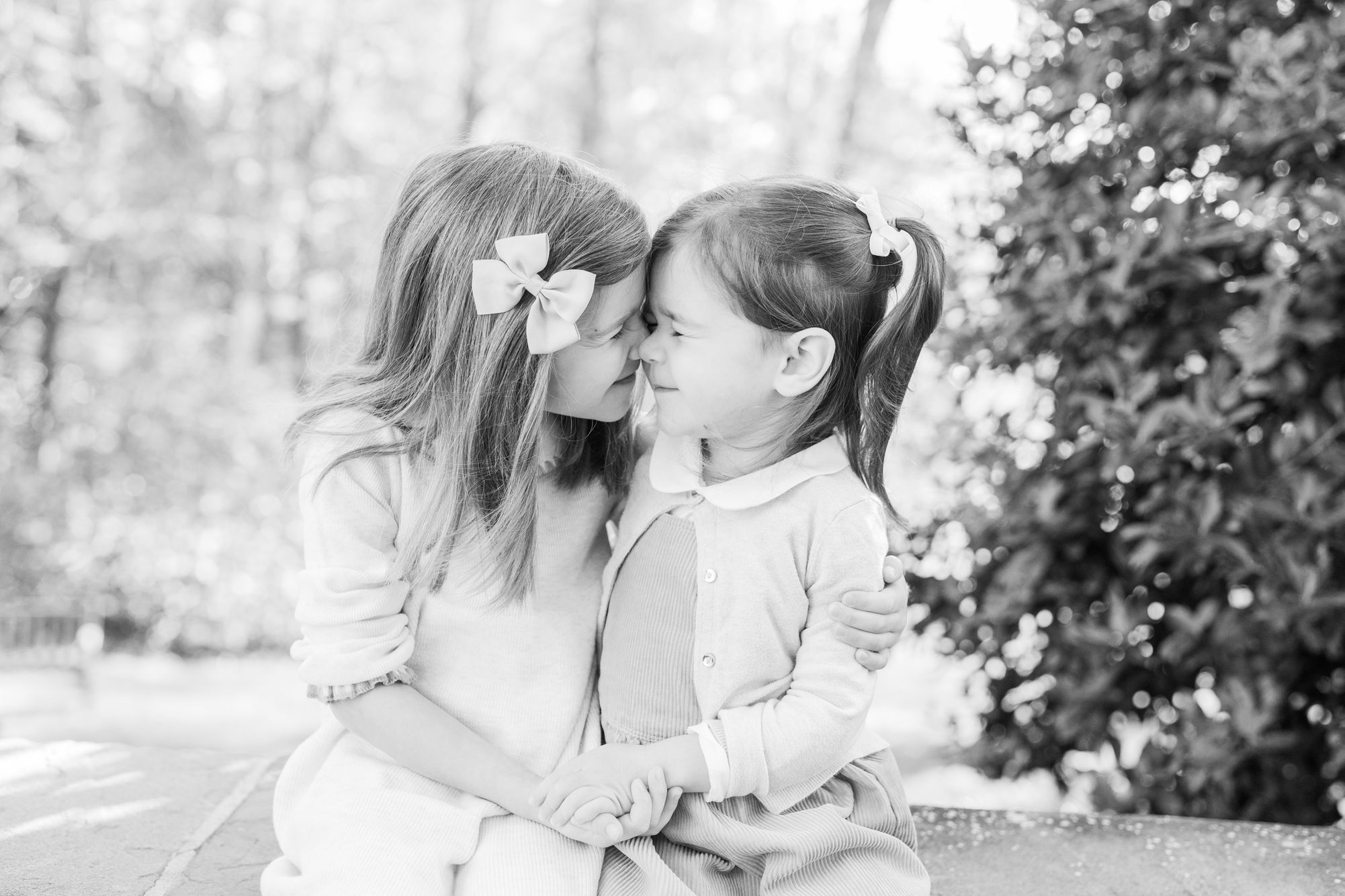 Black and white image of sisters being silly during family session. Photo by LRG Portraits.